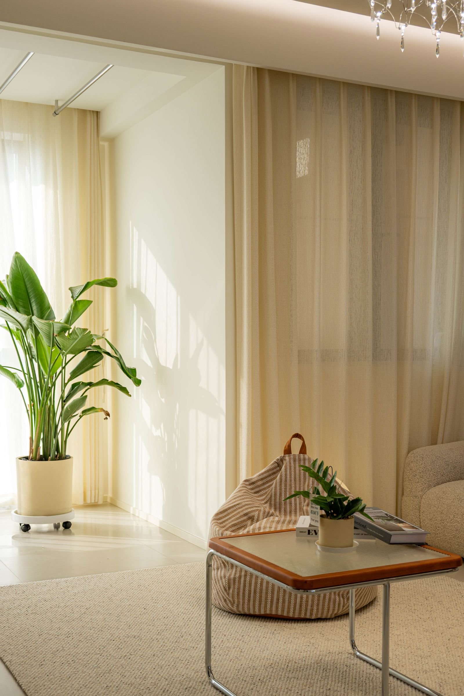 Sala calma e clara com cortina de linho translúcida, planta e almofadas em tons neutros