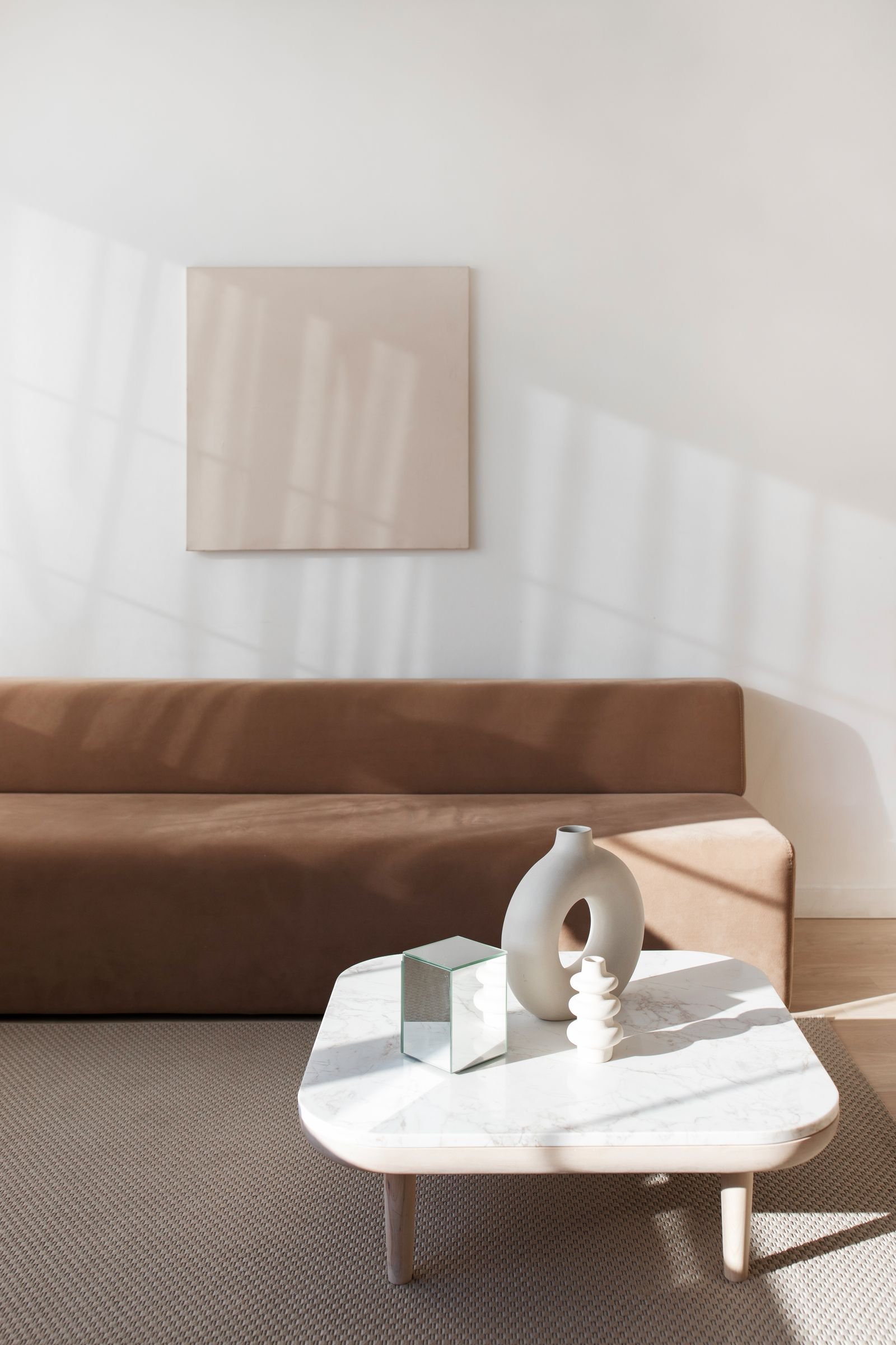 Sala de estar sofisticada e clara, com sofá em tom neutro, mesa de mármore e luz natural suave