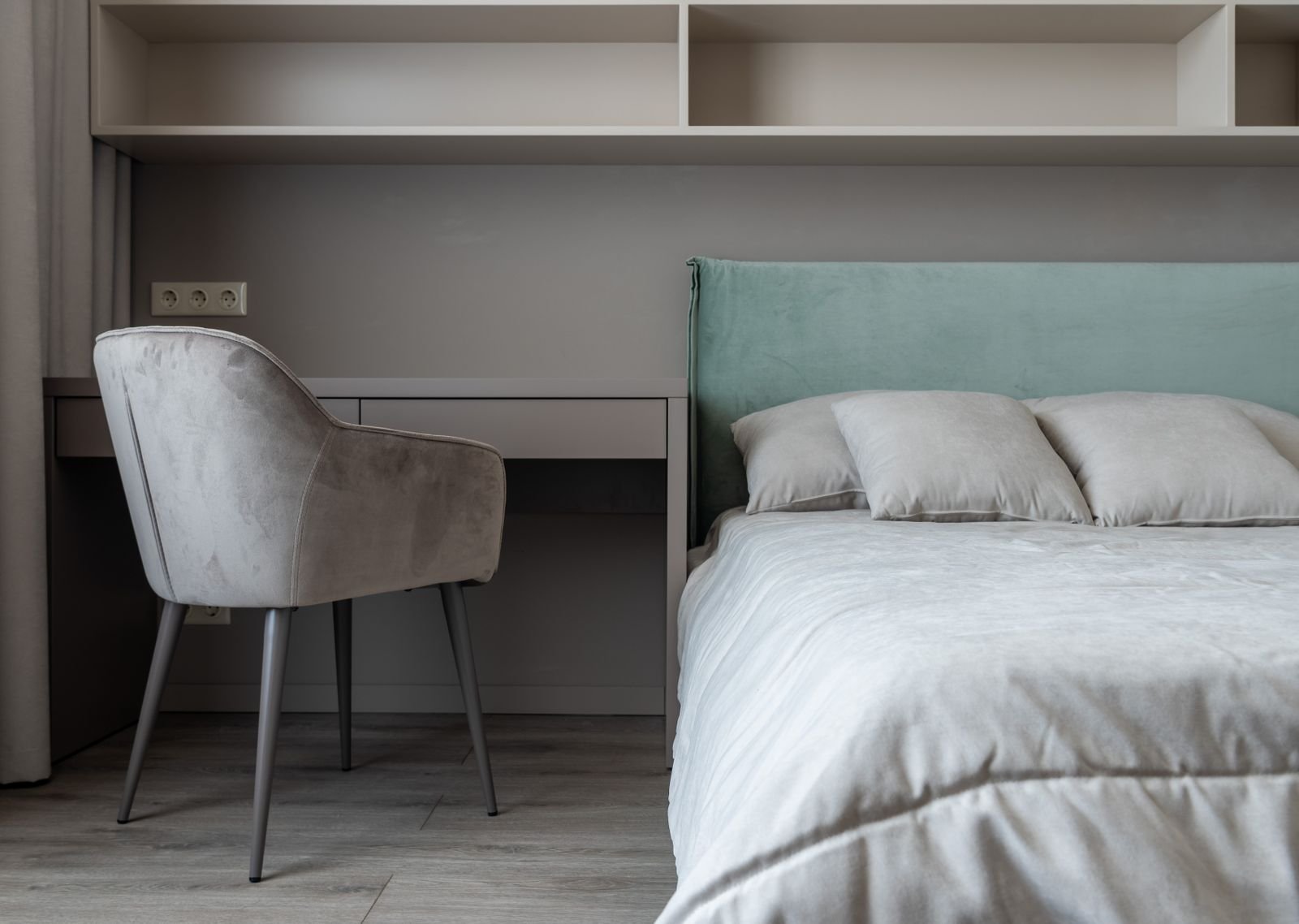 Quarto moderno com cabeceira de veludo verde firme contra a parede, cama arrumada e luz suave