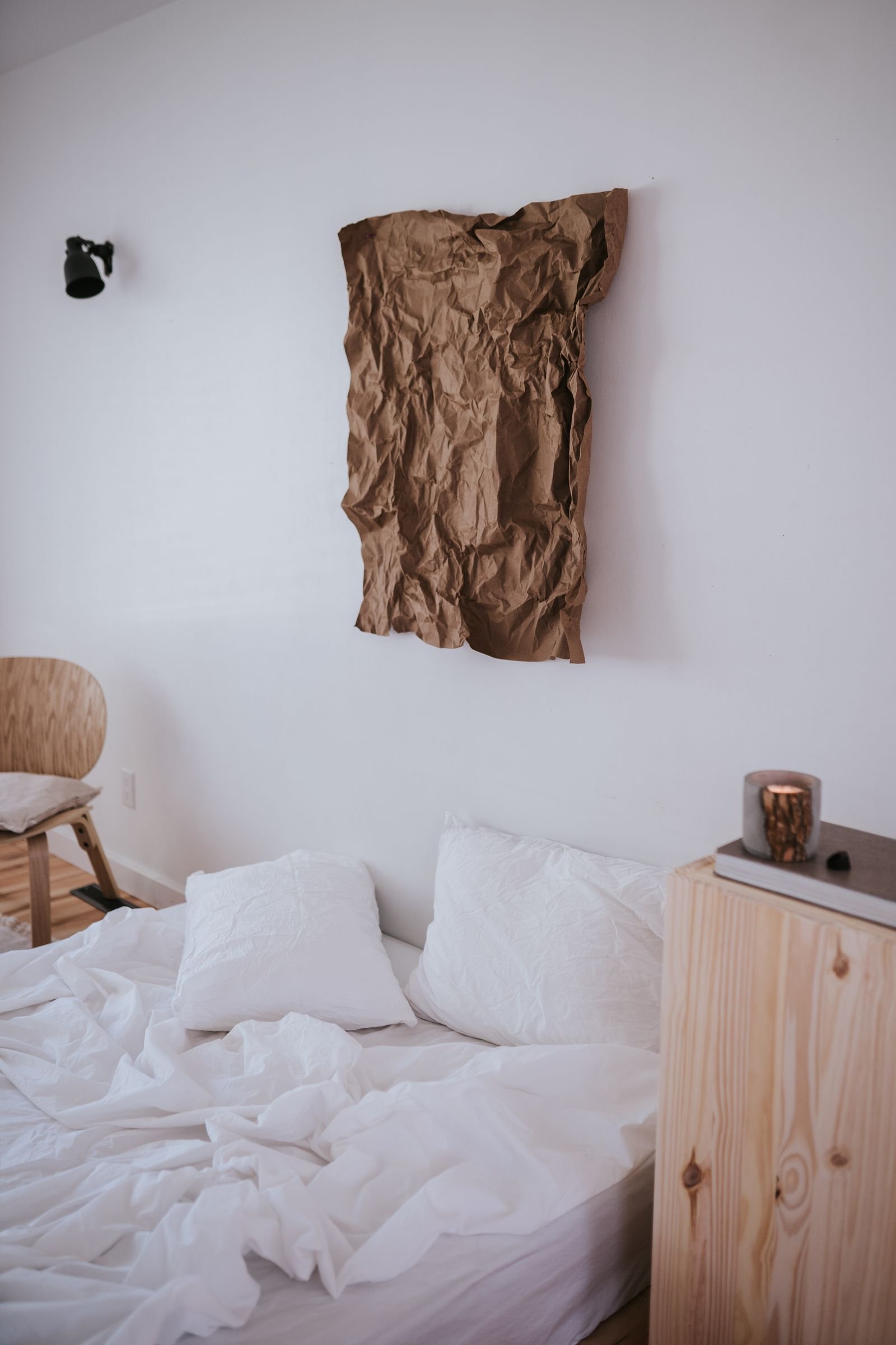 Quarto claro e sereno, com roupa de cama branca, mesa de cabeceira de madeira e luz natural suave