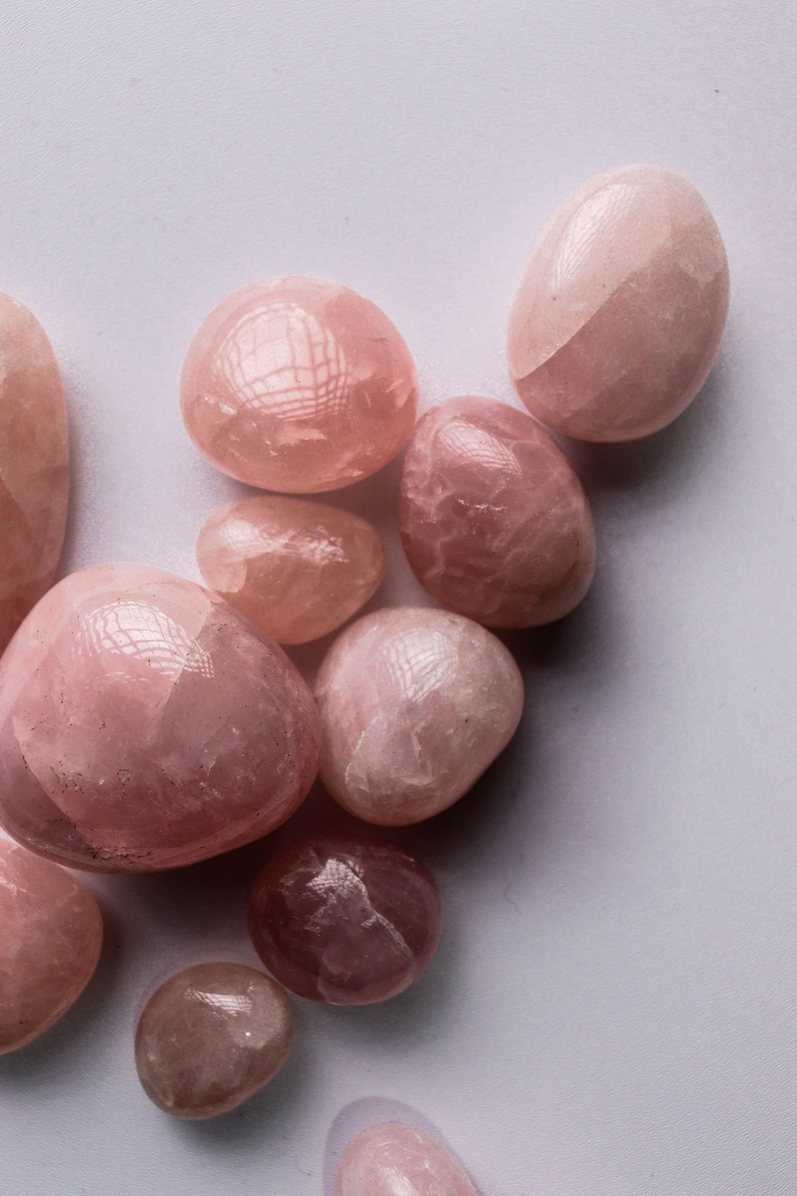 Pedras de quartzo rosa de diferentes tamanhos, em tons claros, sobre superfície neutra