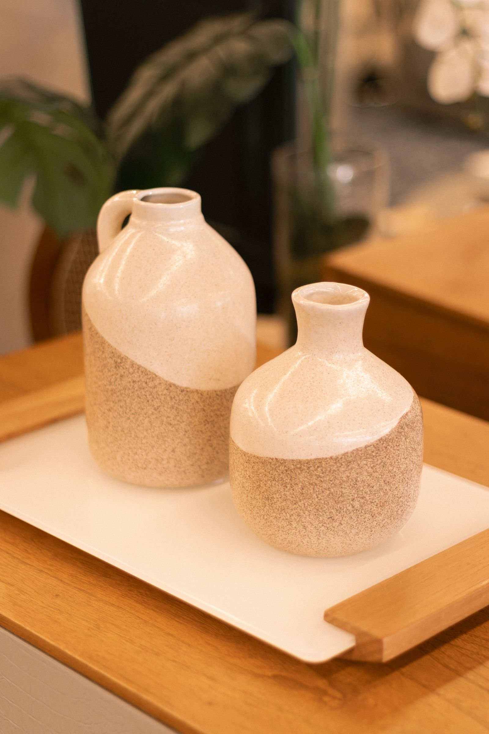 Dois vasos de cerâmica artesanal, um maior e um menor, sobre bandeja de madeira